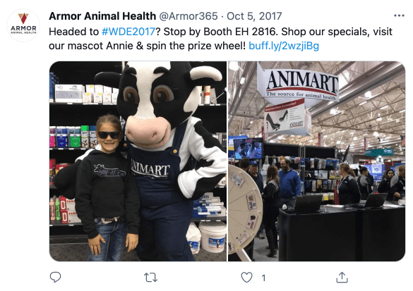 A creative trade show booth idea during an event: Screenshot of a tweet with a photo of a trade show booth with a  cow mascot. It reads: Headed to #WDE2017? Stop by Booth EH 2816. Shop our specials, visit our mascot Annie & spin the prize wheel! https://buff.ly/2wzjiBg.