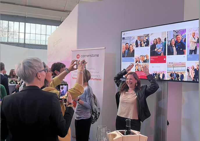 Attendees taking photos in front of a corporate photo booth screen at a conference, capturing user-generated content for display.