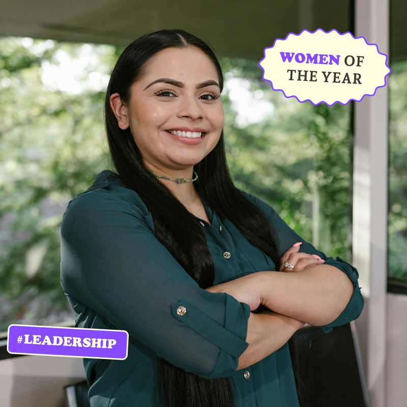 A smiling woman with a badge reading "Women of the Year" and a hashtag "#Leadership" as an example of the type of empowering props one can add to an event photo booth.